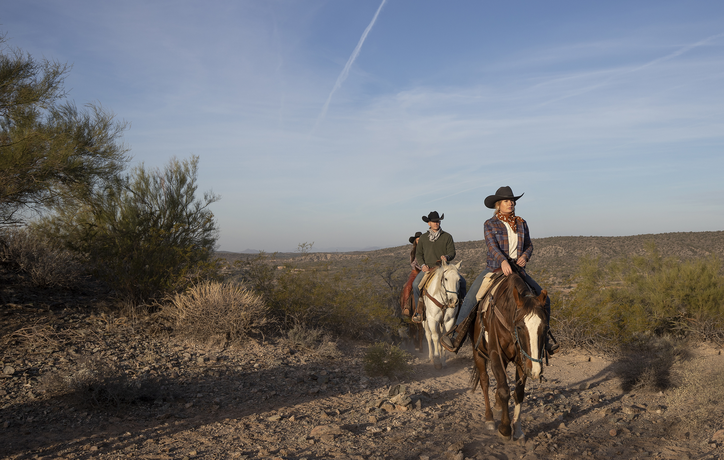 Horseback riders cross the Arizona desert during a dude ranch vacation.