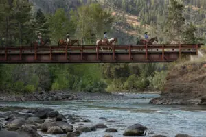 Horseback riders cross a bridge at Blackwater Creek Lodge & Guest Ranch.